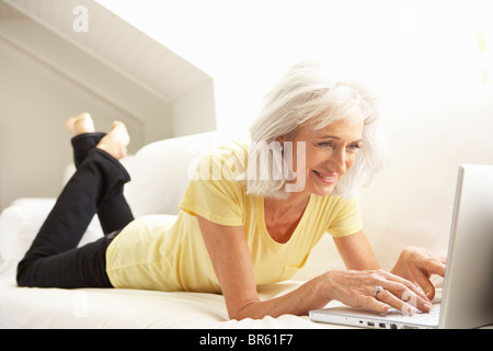 Senior Woman Using Laptop Relaxing Sitting On Sofa At Home Stock Photo