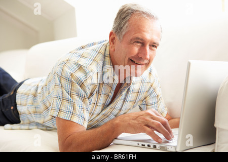 Senior Man Using Laptop Relaxing Sitting On Sofa At Home Stock Photo
