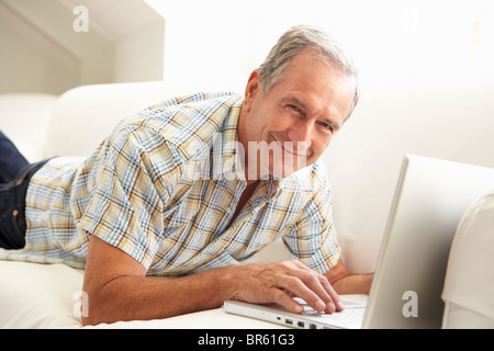 Senior Man Using Laptop Relaxing Sitting On Sofa At Home Stock Photo