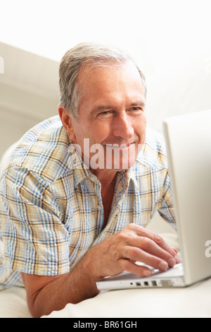 Senior Man Using Laptop Relaxing Sitting On Sofa At Home Stock Photo