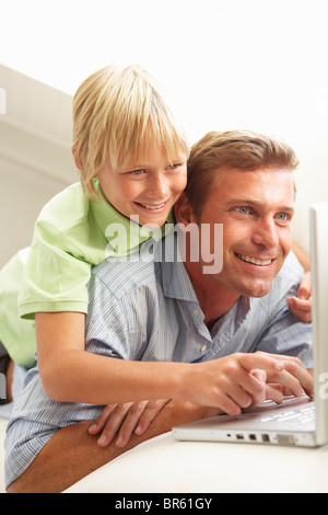 Father And Son Using Laptop Relaxing Sitting On Sofa At Home Stock Photo