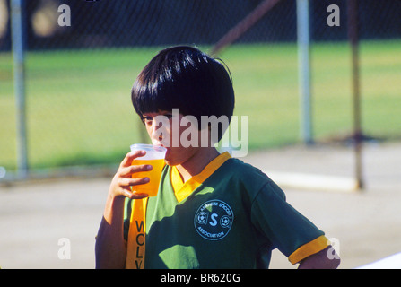 Asian boy drinks juice during break in soccer game. Stock Photo