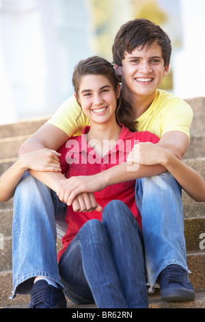 Teenage Couple Sitting On College Steps Outside Stock Photo