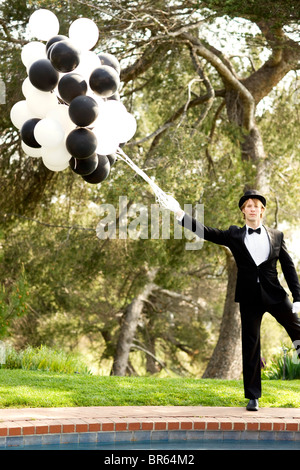 Caucasian man in tuxedo holding bunch of balloons Stock Photo