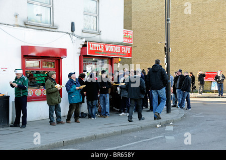 Football fans eating outside the Little Wonder Café on Arsenal Football Club match day Holloway London UK