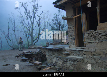 A Pashtun man stands in the rain and mist outside of a home damaged in the earthquake-he and his family have just arrived back Stock Photo