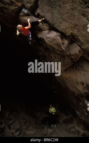 A young woman climber lead climbing on an overhanging rock climbing route. Stock Photo