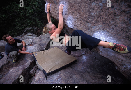 A man spots a young female rock climber on an overhanging bouldering route. Stock Photo