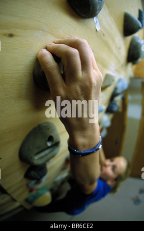 A female rock climber works out on a home climbing wall. Stock Photo