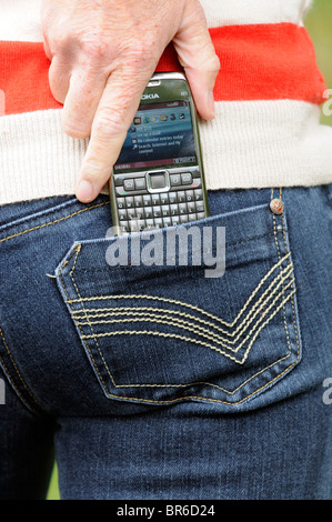 Woman putting a Nokia E71 model mobile phone into her blue jeans pocket Stock Photo