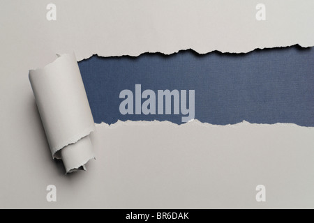 Torn paper with opening showing dark blue background Stock Photo
