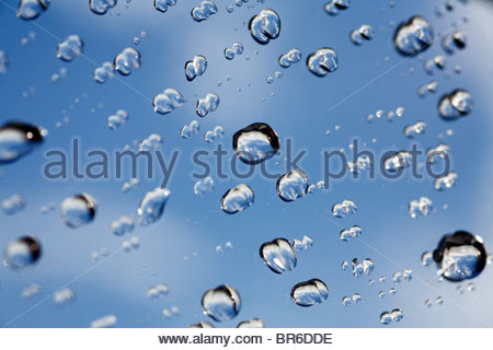 Raindrops on window pane with blue sky Stock Photo