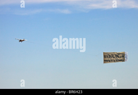 Airplane towing advertising banner over beach at Long Beach Long Island NY Stock Photo