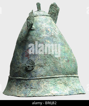 A Hellenistic Pilos type helmet, 4th century B.C. Bronze helmet with a tall conical skull. The flaring rim bordered by two raised bands. Pairs of holes on either side with soldered, pierced disk appliqués bearing wheel decoration. The crest reinforced by a cap with chase decorated edge (ancient repair?) topped by a riveted crest holder. Fragments of two riveted horn attachments on either side. Height 23.5 cm, weight 798 g. Blue-green patina with soil occlusions. The skull glued and supplemented. The inside reinforced with fibreglass. Slightly deformed, intensel, Stock Photo