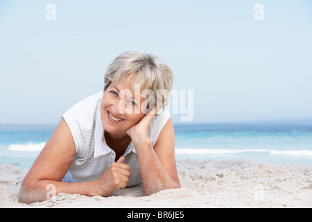 Senior Woman Relaxing On Sandy Beach Stock Photo