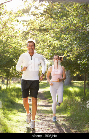 Middle Aged Couple Jogging In Park Stock Photo