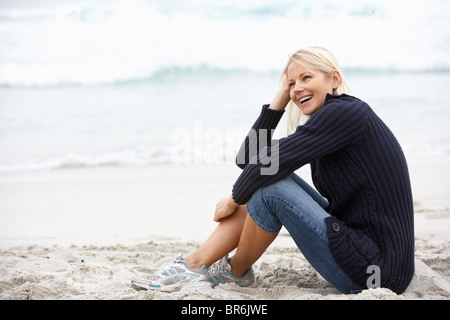 Young Woman On Holiday Sitting On Winter Beach Stock Photo