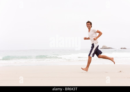Young Man Running Along Winter Beach Stock Photo