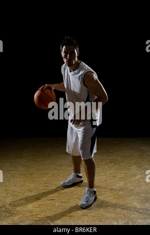 A basketball player dribbling a ball, portrait, studio shot Stock Photo