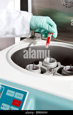 A lab technician putting a vial of blood into a centrifuge, close-up of hand Stock Photo