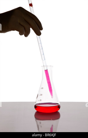 A lab technician using a dropper to put fluid into a beaker, close-up of hand Stock Photo