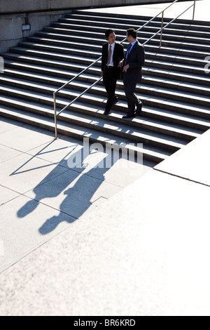 Two businessmen walking down stairs, outdoors Stock Photo