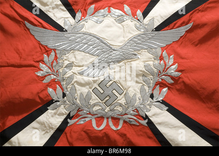 A flak artillery banner., Made entirely of silk with silver fringe on three edges. Red with a white disk on both sides surrounded by a silver embroidered laurel wreath. One side displays a silver embroidered Luftwaffe eagle in the centre spreading its wings beyond the wreath, and the other disk bears an iron cross. Four diagonal white rays with black edging, widening toward the corners, each bearing a silver-edged, black silk swastika at the corner. Unfaded colours. Unnoticeable traces of nails on the pole sleeve, barely noticeable stains. Dimensions 140 x 125 , Stock Photo