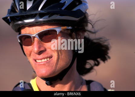 A portrait / headshot of a female mountain biker with a helmet and sunglasses. Stock Photo