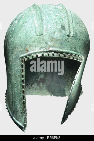 An Illyrian helmet, 6th century BC. Bronze. Spherical skull with a broad crest base contoured by double ridges, shallow side cutouts and short neck-guard. Surrounded by a a double, raised border - reinforced on the forehead - with lentil-headed decorative pins. The tips of the cheekpieces pierced for attachment of the chin strap. Heigth 23 cm, weight 670 g. Slightly deformed, metal in good condition, blue-green patina with soil sedimentations. The interior, above the face cutout, at the rear of the crest, on the left side and at the neck (3.5 cm long crack) sta, Stock Photo