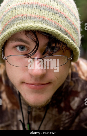 A young male college student gets wet while pitching a camp in the Maine North Woods. Stock Photo