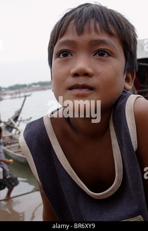 A young boy takes a break from his job as a fisherman on the shore of the Mekong River in Kampong Cham, Cambodia. Stock Photo
