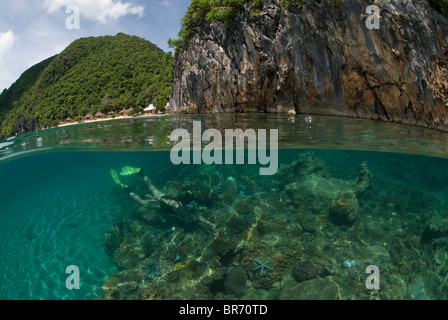 Split-level showing snorkeler, coral reef and limestone cliffs in the Caramoan Peninsula, Camarines Sur, Luzon, Philippines 2008 Stock Photo