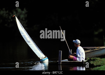 Young boy sailing his radio controlled 12 Metre model yacht on a lake in Stowe, Vermont, USA Stock Photo