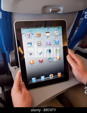 Woman using iPad computer tablet when flying on passenger aircraft Stock Photo