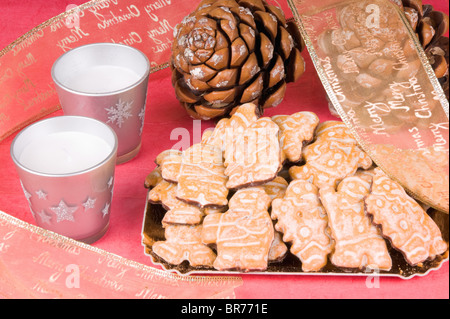 Christmas composition: gingerbread men, Christmas ribbon, pine cones and candles. Studio shot over red background Stock Photo