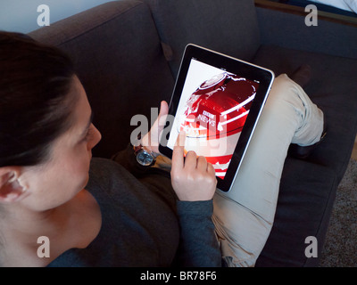 Woman using iPad computer table at home to browse BBC news website Stock Photo