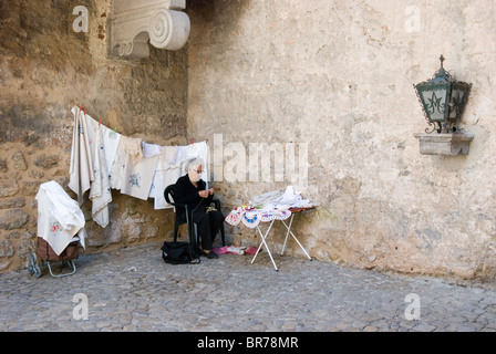 The mediaeval fortified city of Obidos, Portugal. Ancient woman works in Porta da Vila southern town gate. Stock Photo