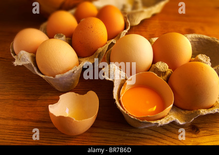 Free range eggs, one cracked with a yoke, in a coutry kitchen setting Stock Photo