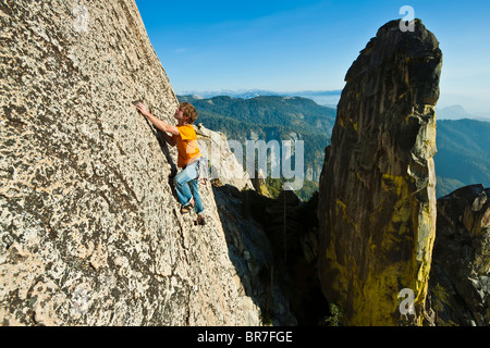 Male climber clings to a steep rock face. Stock Photo