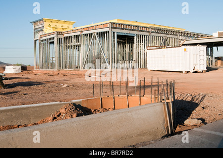 A framework of structural steel is constructed to support a wall in a new bank building. Concrete curb forms in the foreground. Stock Photo