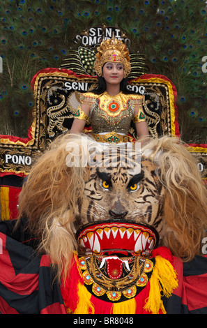 A Female Reog Dancer is sitting on a Sisingaan, while waiting to perform. Reog is Indonesian traditional dance from Ponorogo, East Java, Indonesia. Stock Photo