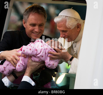 With Georg Gänswein, Pope Benedict XVI kisses a baby lifted up to his open car window as he arrives in Popemobile at Hyde Park. Stock Photo