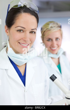 Two attractive smiling female scientists or women doctors wearing a white coats in a laboratory or hospital Stock Photo