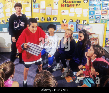 junior high intermediate school boy male read act story book fellow student class laugh happy drama act teacher learn speak Stock Photo