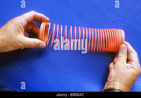 plastic slinky toy spring stretch coil wave effect pulse pattern force energy move science demo experiment Stock Photo