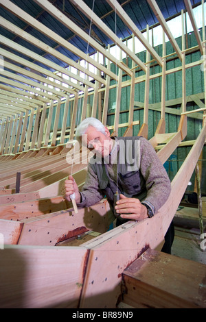 Shipwright at work with a plumb line during construction of a 38-metre wooden motorboat, at a boatbuilders in Fiumicino, Rome. Stock Photo