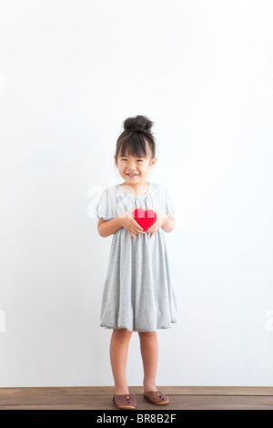 Portrait of girl holding red heart, white background Stock Photo