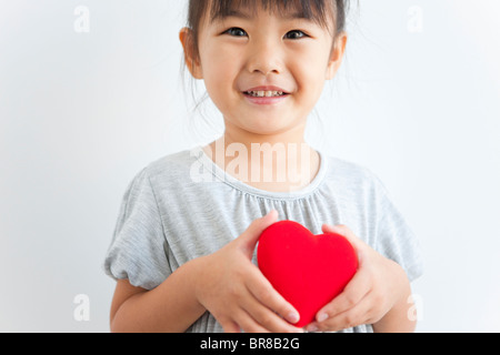 Portrait of girl holding red heart, white background Stock Photo
