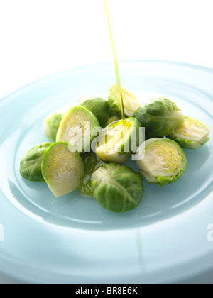 Salad dressing being poured on Brussels Sprouts