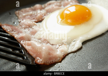 Bacon and egg being fried in pan, close up Stock Photo
